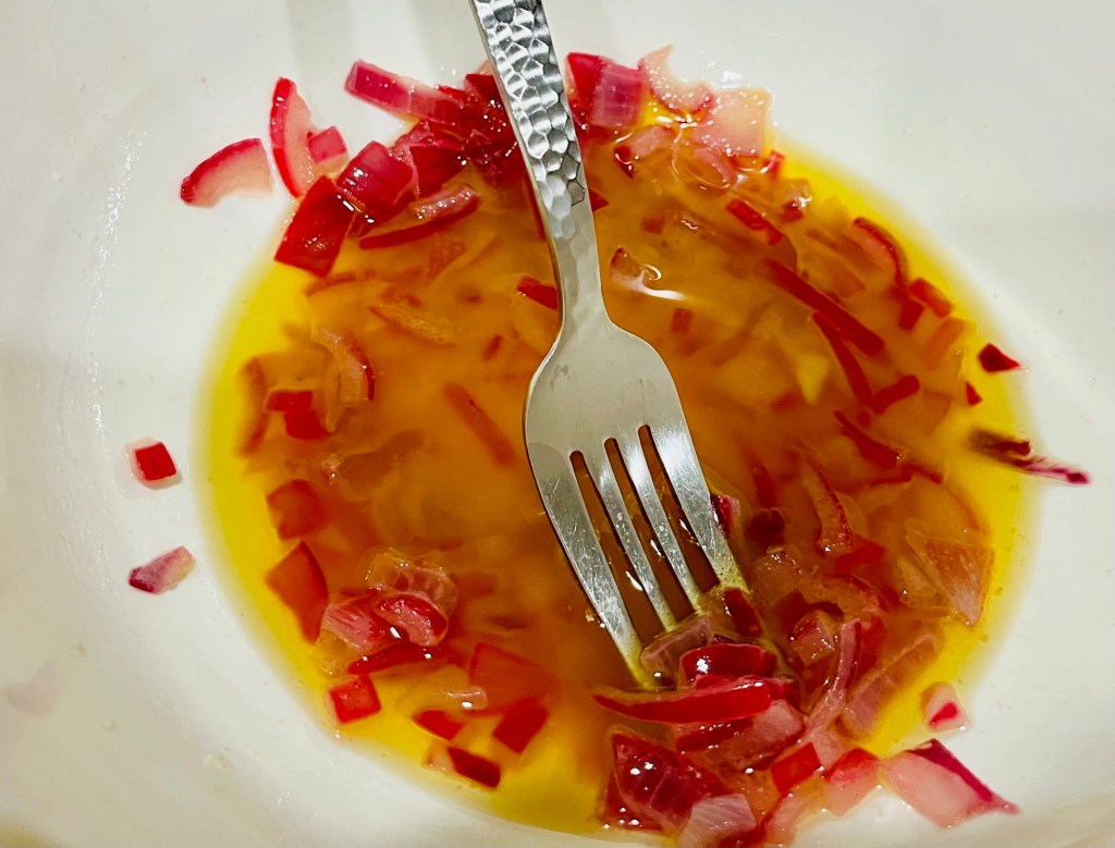 Making the salad dressing with olive oil and onion.