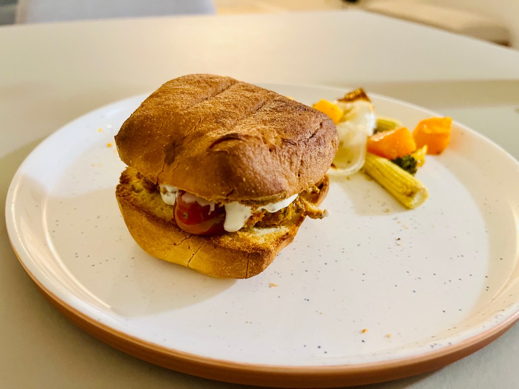 Gluten-free bun with chicken shawarma, roasted vegetables, tzatziki sauce